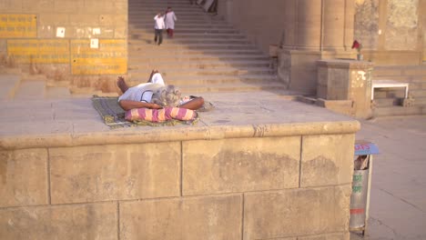 elderly indian woman sunbathing on a wall