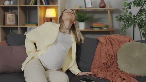 pregnant woman experiencing back pain at home