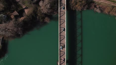 the scene is captured from above as the cars drive over a bridge spanning a body of water