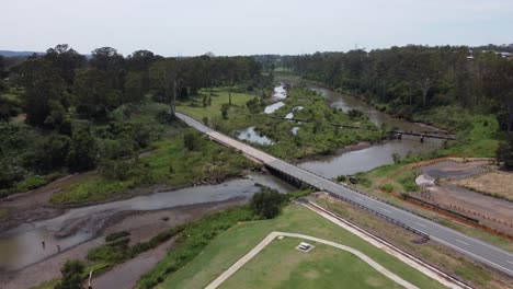 aerial view of a brown river with a bridge and a pipeline crossing over it