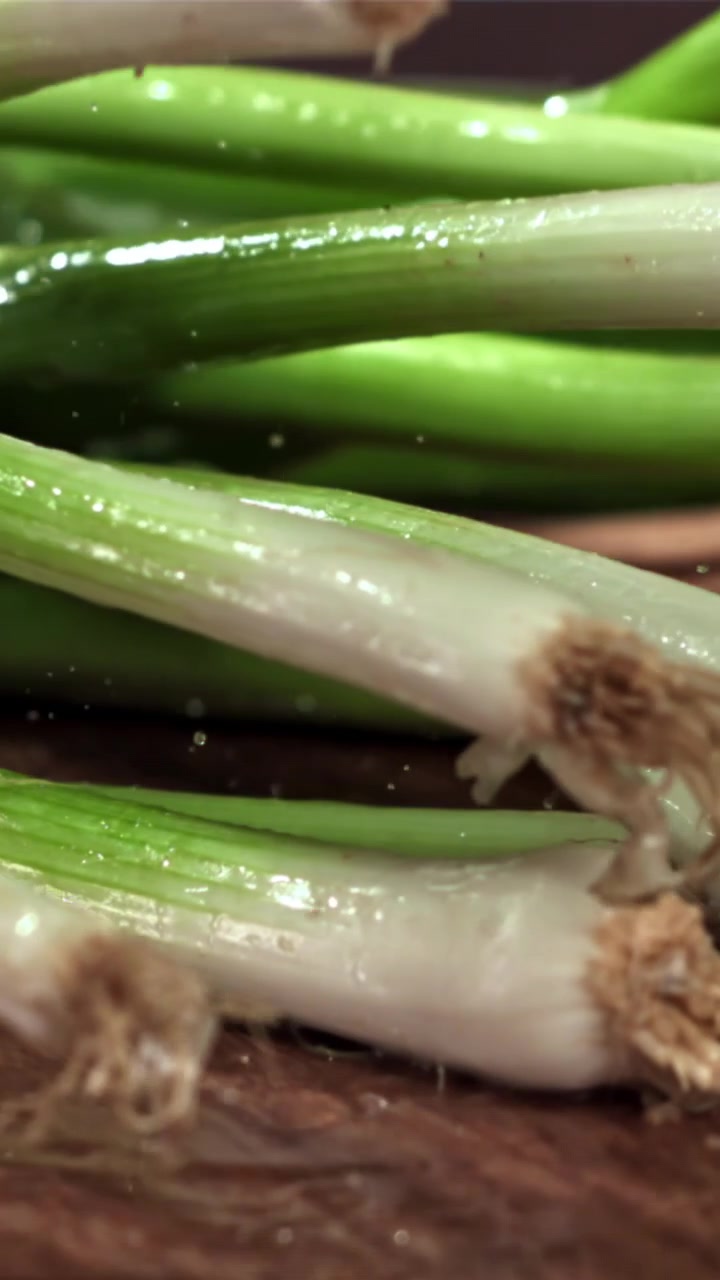 Vertraagde beweging van verse lente-uitjes die op een houten oppervlak vallen