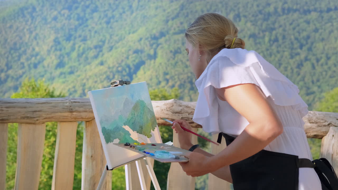 여자 가 야외 에서 산의 풍경 을 그린다