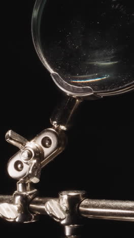 shiny soldering tool of engineer with big magnifier glass on black background. professional jeweler instrument illuminated with bright studio light macro