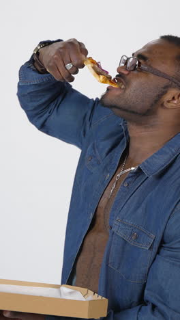 african man eating pizza in studio. portrait of muscular african american man with shirt eating pizza