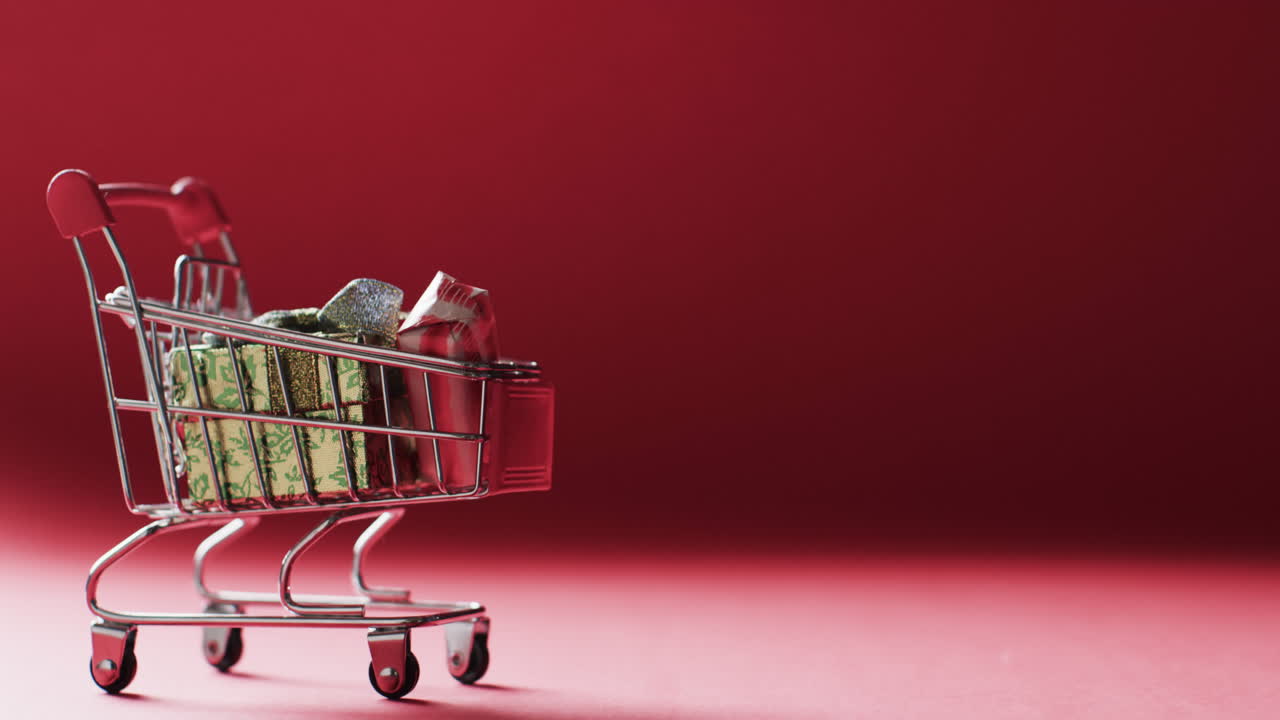 video de un carrito de compras con regalos de navidad y espacio de copia en fondo rojo