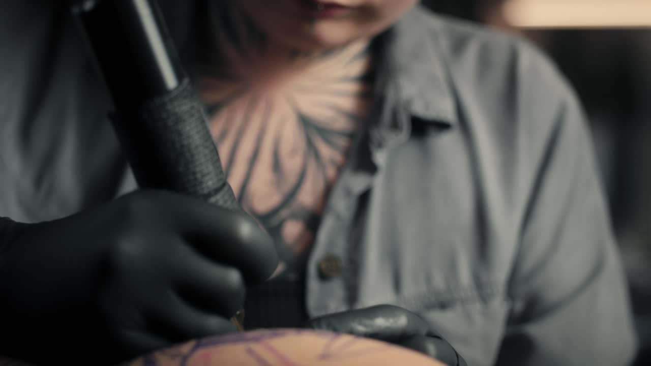 Donna concentrata che tatua le braccia del suo cliente