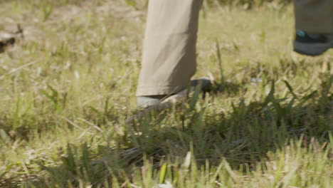 primer plano de dos excursionistas irreconocibles caminando por un sendero cubierto de hierba en un día de otoño