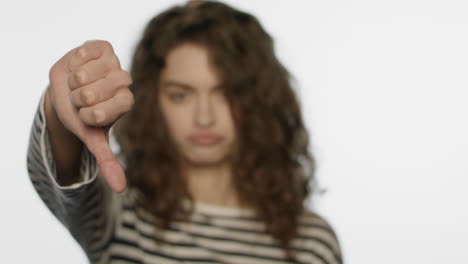 sad girl showing thumbs down in studio. upset woman showing dislike sign hand