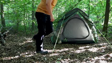 tourist man adjusting the tent at a campsite in the woods-1