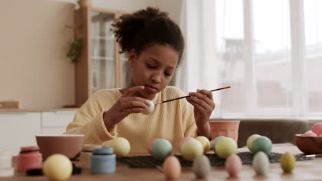 chica africana coloreando huevos con pintura
