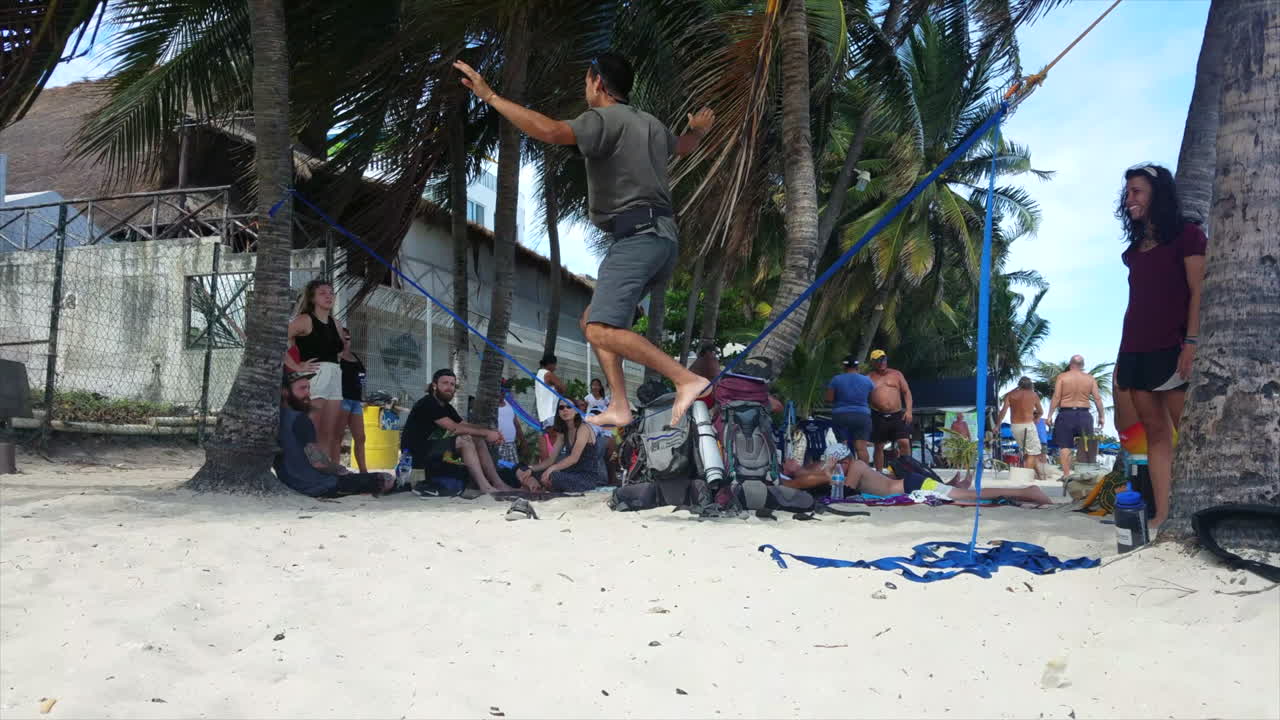 Man In Mexico Walking And Balancing Across A Tight Rope With An Audience On The Beach