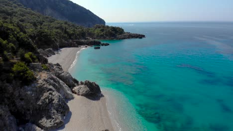 secret sandy beach bordered by rocks and green hills washed by clean turquoise sea water