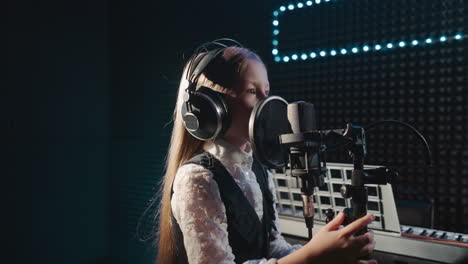 girl during vocal lesson in recording studio. young girl student with loose hair practices tones for good sound. audition before taking part in talent show