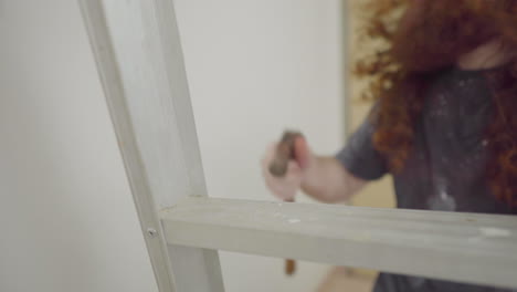 home repair man close on climbing down ladder focus on hammer shallow depth of field