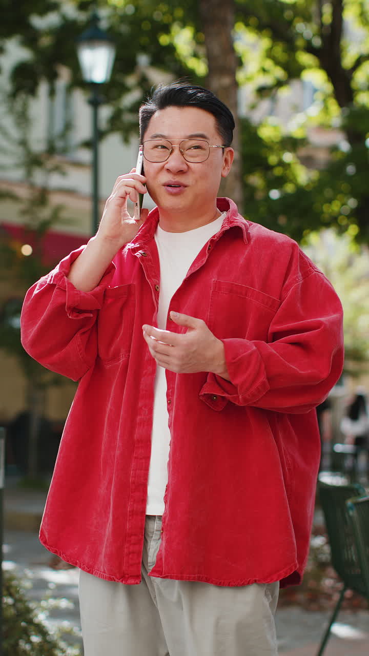 행복한 중국인 남자가 원격 통화를 하고 스마트폰으로 이야기 하고 있습니다. 도시 거리에서 좋은 소식, 소문입니다.