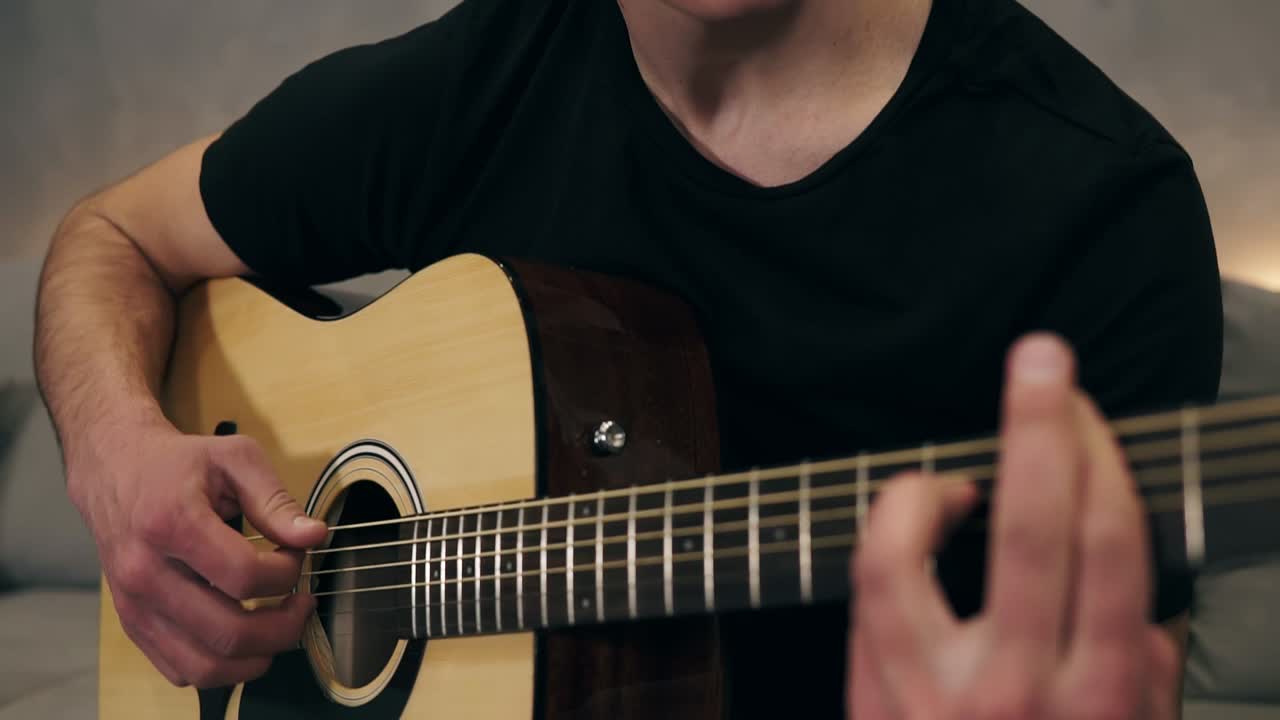 tipo caucásico con camiseta negra tocando la guitarra. primer plano de manos masculinas tocando la guitarra acústica. guitarrista profesional músico tocando solo en la guitarra. primer plano de dedos del hombre músico y cuerdas. cámara lenta