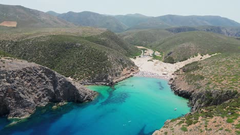 Cala-Domestica-Strand,-Blaue-Bucht-Und-Grüne-Berge-In-Sardinien,-Italien---4k-Antenne