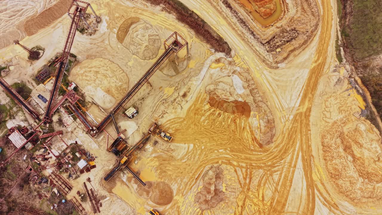 Sand quarry with equipment and trucks working on-site in a rural area