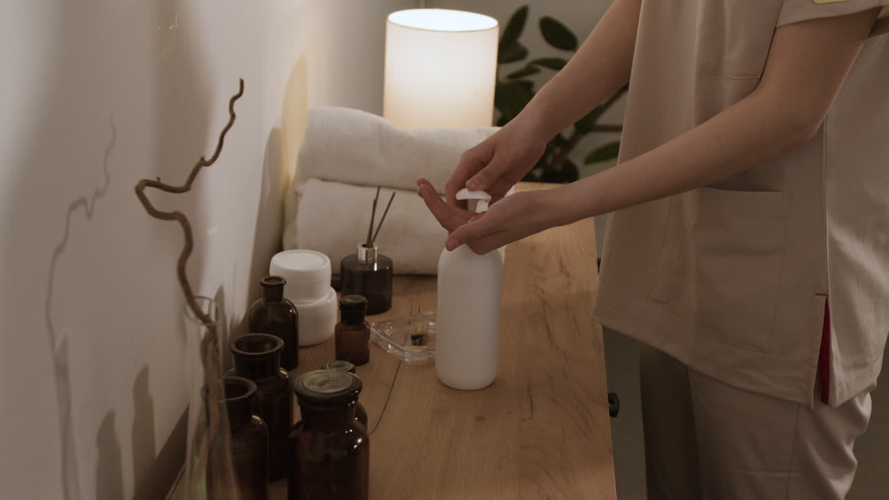 A person prepares for a spa or massage treatment, with various wellness products on a wooden counter.