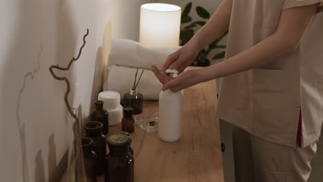a person prepares for a spa or massage treatment, with various wellness products on a wooden counter.