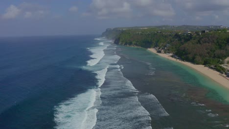 beautiful shot in melasti bali beach drone moving forward, water waves reaching the shore of the beach