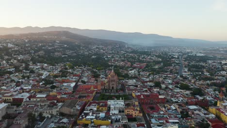 drone flies above san miguel de allende city center, mexico, mountain landscape in background