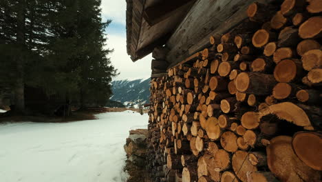 winter scene with firewood stack and cabin in mountains