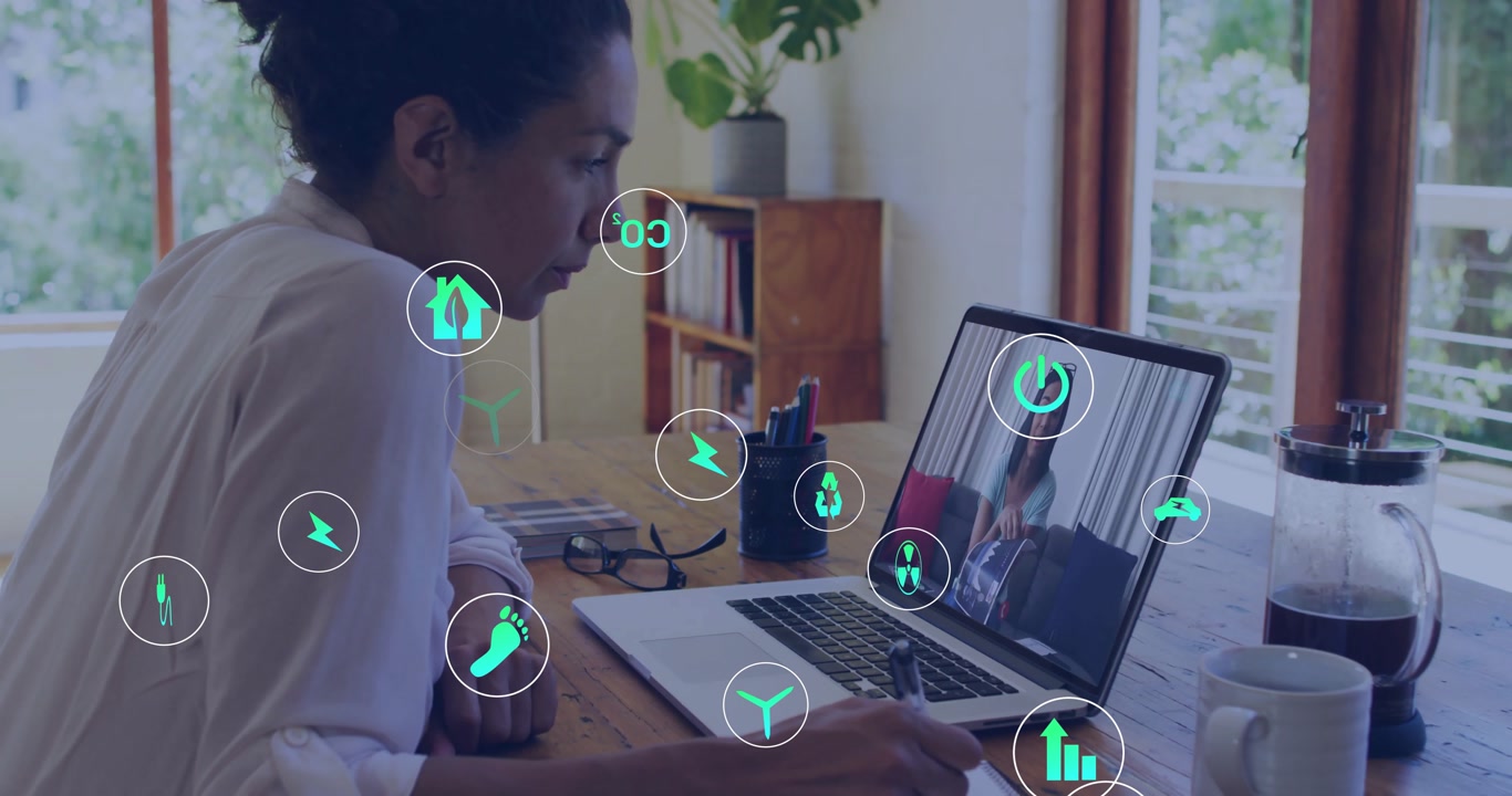 woman picking pen, writing notes during finance meeting while tech icons floating around laptop