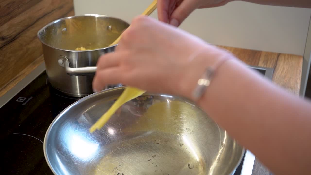 mano de mujer poniendo una rebanada de masa de tortilla en una sartén