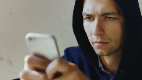 portrait of a very tired young man trying to read a message on the phone concept problems crime