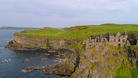 Dunluce-Castle,-Northern-Ireland-aerial-push-in-J-turn-over-the-sea-towards-structure