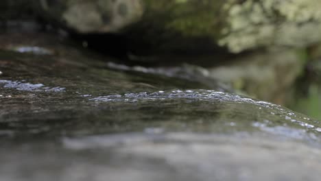 close up of water trickling down rock at waterfall slow motion