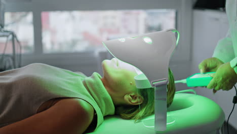 cosmetólogo aplicando un tratamiento facial con máscara de led en un primer plano de la clínica. fototerapia