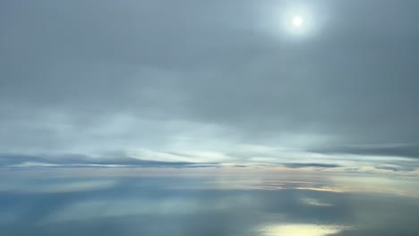 flying over the mediterranean sea under a layer of clouds that hides the sun