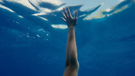 arm reaching towards the surface from underwater