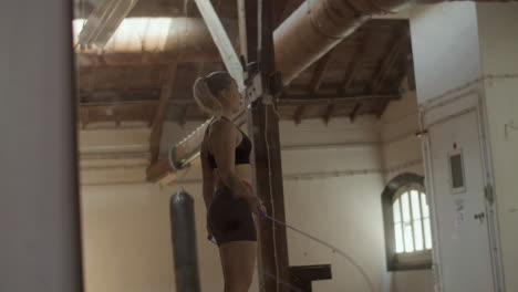 side view of athletic woman jumping rope in practice room