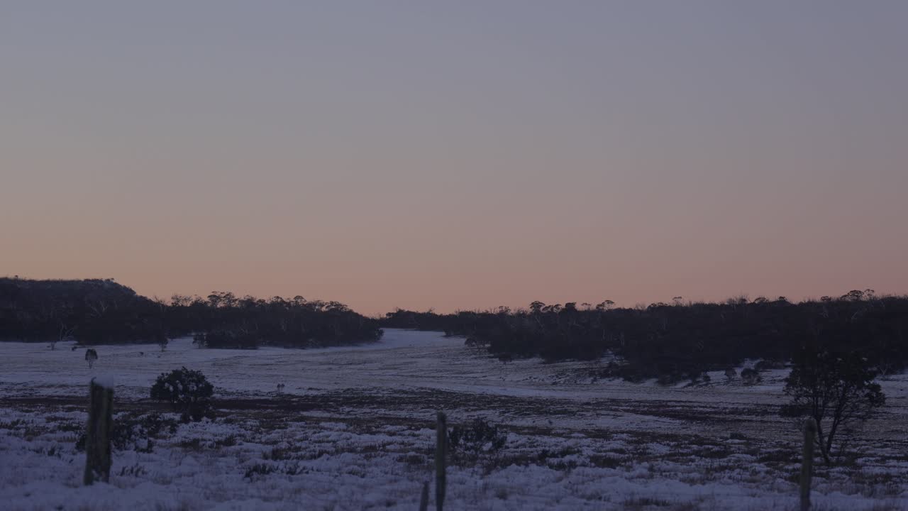 Solnedgang over en victoriansk højslette med sne, der dækker landskabet.