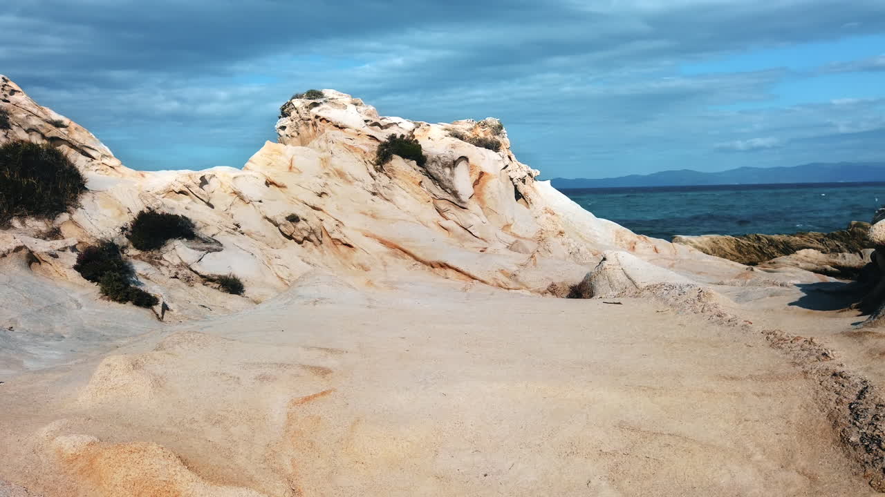 Aegean sea coast with greenery, rocks and bushes, blue water, Greece. Slow motion