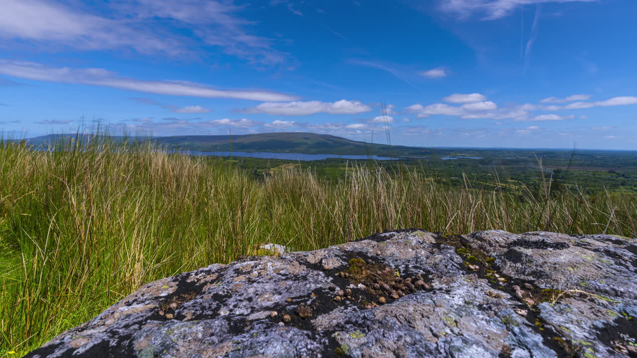 Time lapse of rural landscape with a single massive boulder rock in grassland hillside on a spring sunny day in Arigna mountains in county Leitrim in Ireland