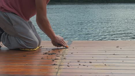 man using tool to scrap mastic sealant off cabin roof planks