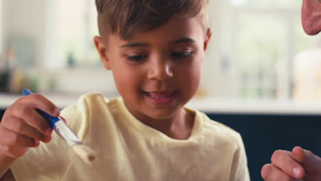 Close-Up-Of-Mature-Father-At-Home-In-Kitchen-With-Son-Painting-Picture-Together