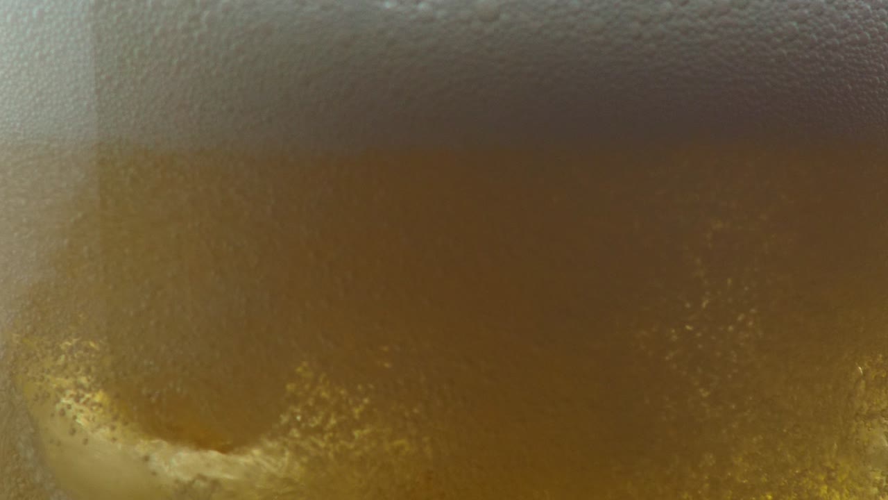 cerca de una bebida gaseosa de lúpulo dorado que se vierte en un vaso con hielo
