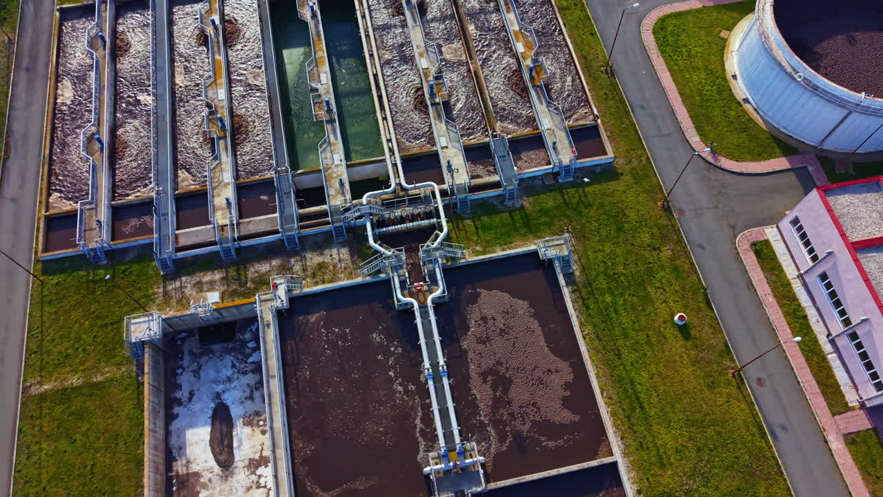 Water treatment plant in operation with large tanks and pipes for processing wastewater during daylight hours in an industrial area