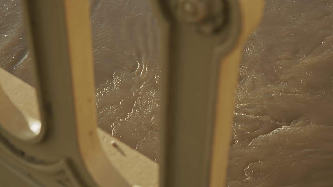 Close-up View of Flowing Water Through a Metal Fence
