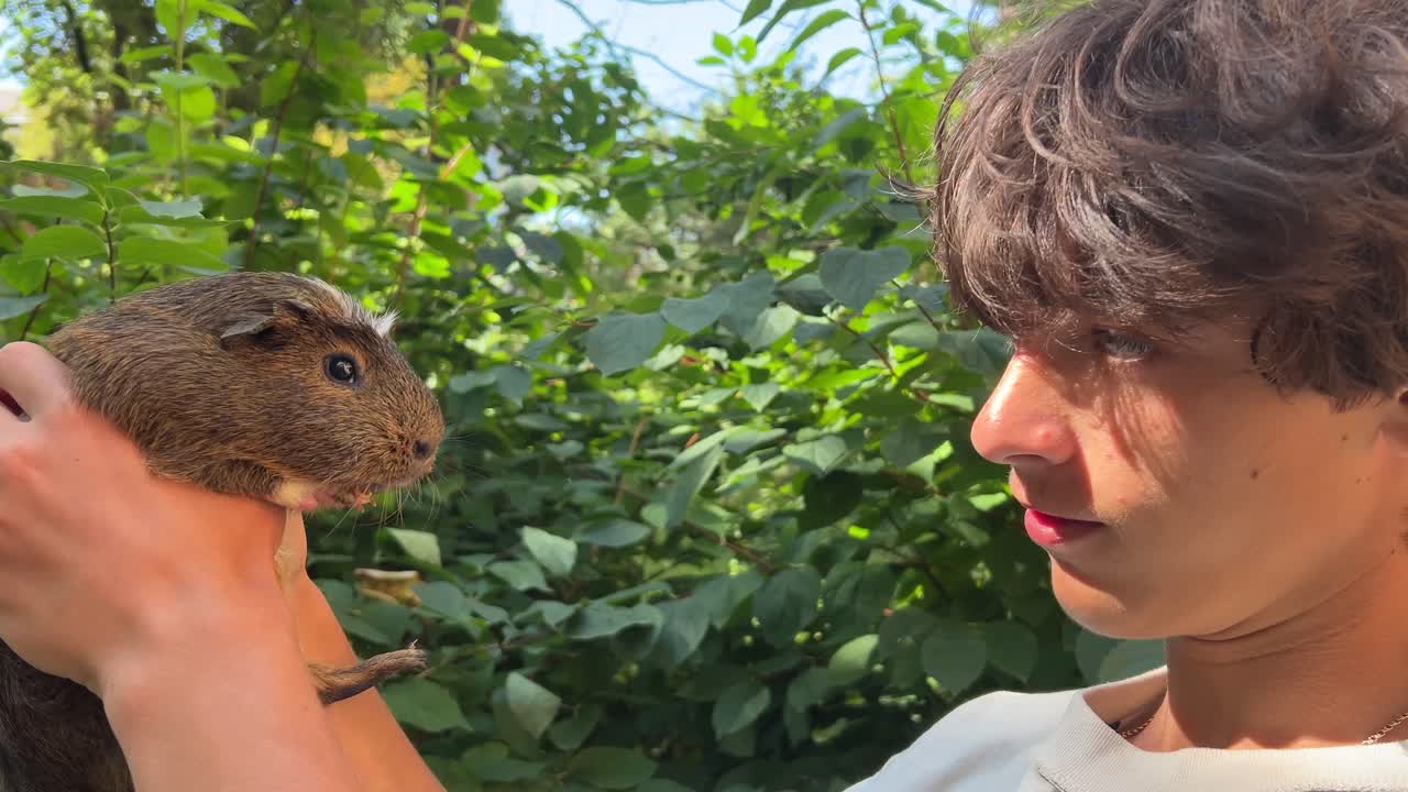 adolescente sosteniendo un conejillo de indias en un jardín
