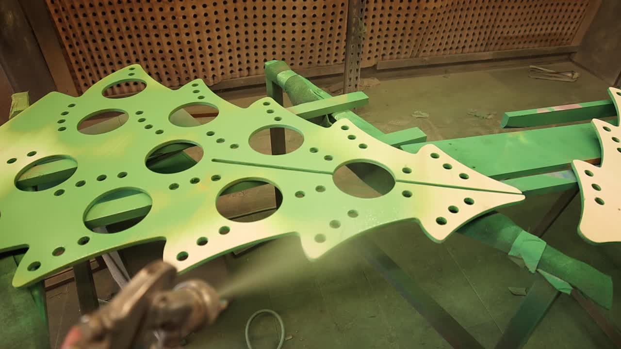 maestro de cultivos con pistola de pintura pintando un árbol de metal ornamental