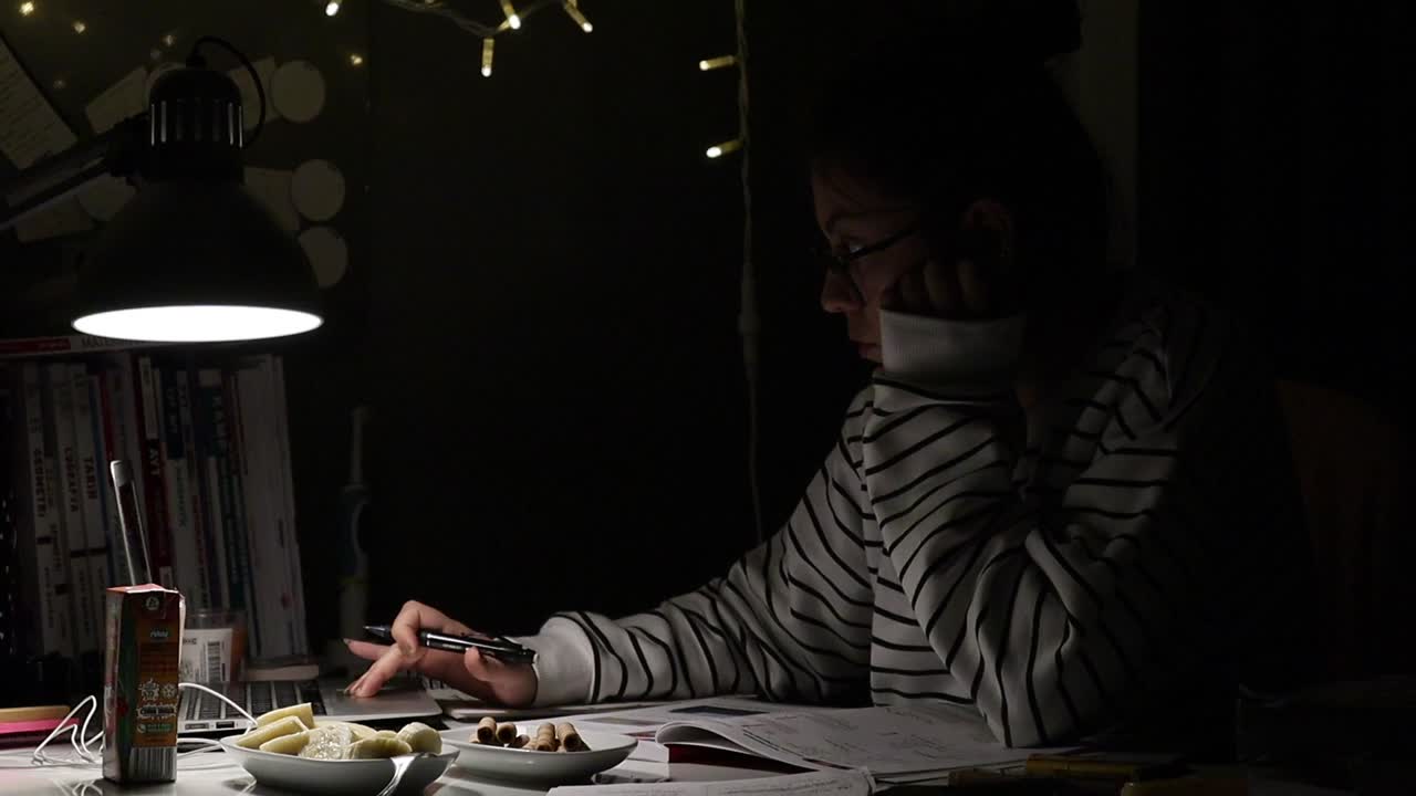 A student scrolling laptop studying at night