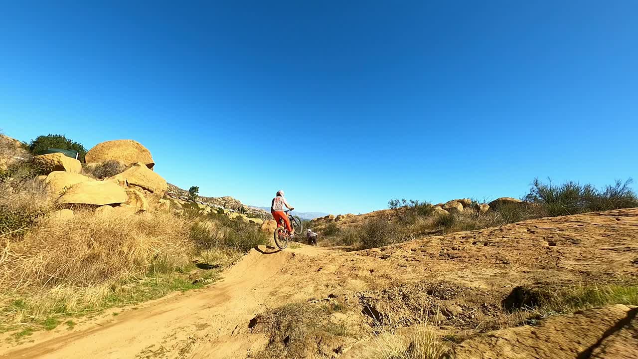 Drone chasing fast mountain bikers off jumps downhill