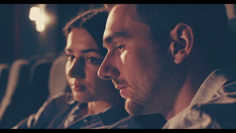 couple and friends watching a movie in a dark cinema hall