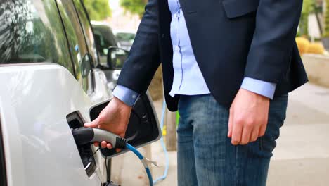 hombre de negocios cargando un coche eléctrico en la estación de carga 4k